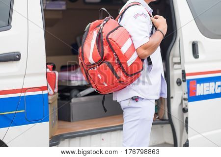 male nurse carry nursing bag on his back standing beside ambulance prepare for helping people