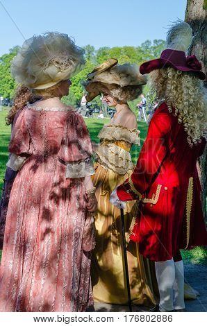 Saint Petersburg, Russia - may 15, 2016: Actors demonstrate vintage clothing 18 century in the Park A man and two women in vintage outfits amid green meadows and blue sky