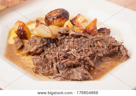 Elegant set of braised potatoes and onions in a white English ceramic dish and indian tablecloth.