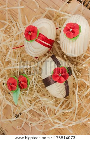 Easter eggs with ribbon and red flowers. Background birch bark and straw