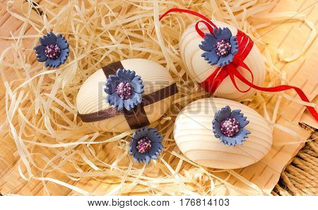 Easter eggs with ribbon and red flowers. Background birch bark and straw