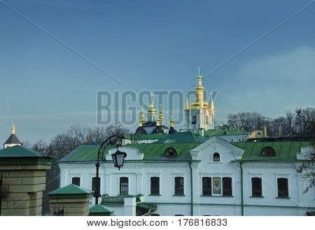 Golden dome with a golden cross on the territory of the Kiev-Pechersk Lavra against the blue sky