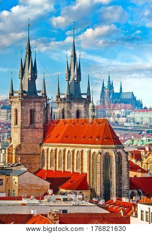 High spires towers of Tyn church in Prague city (Church of Our Lady before Tyn cathedral) urban landscape panorama with red roofs of houses in old town and blue sky with clouds.