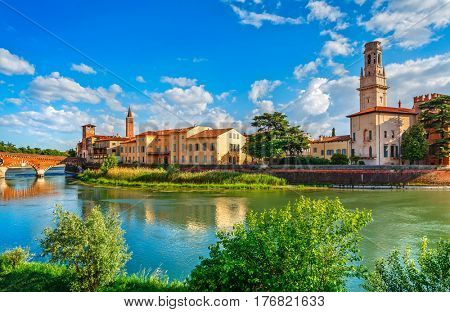 Panoramic view to Bridge Ponte Pietra in Verona on Adige river, Veneto region, Italy. Sunny summer day panorama and blue dramatic sky with clouds. Ancient european italian terracotta color houses.
