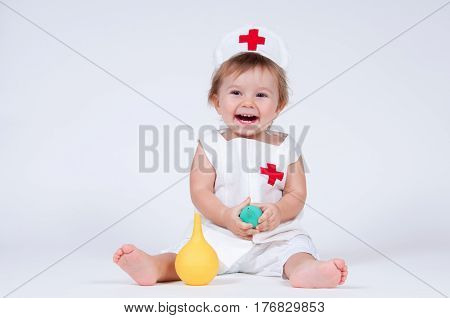 Girl laughs playing nurse with enema in hands.