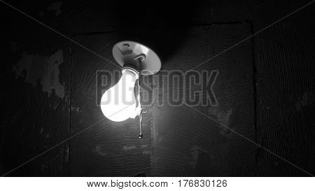 Black and white vintage light fixture incandescent bulb lit up.