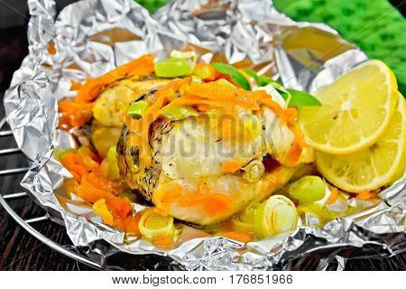 Pike With Carrots And Lemon In Foil On Dark Board
