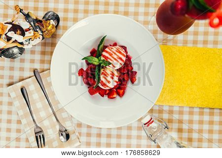 Strawberry ice cream dish with fresh strawberry and green petal serve on decorated with checkered cloth table
