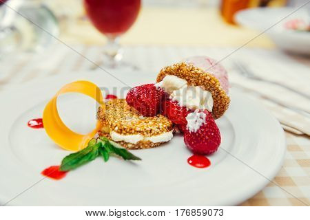 Strawberry ice cream dish with fresh strawberry, fresh cookie and green petal serve on decorated with checkered cloth table