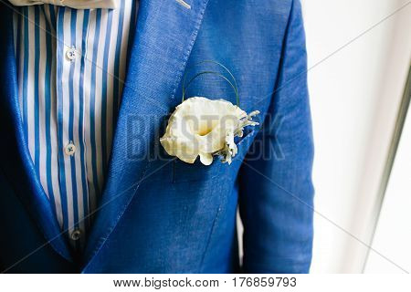 Yellow boutonniere pinned to a grooms blue jacket