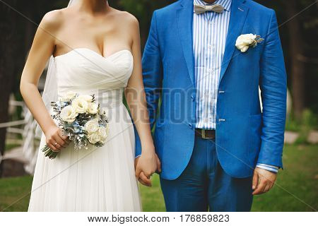 Young wedding couple hold each other on by hands and walking in park