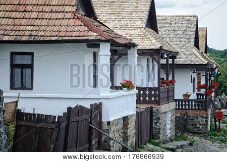 Row of farmhouses with porches decorated with flowers in Holloko, Hungary
