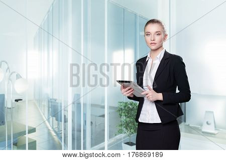 Young attractive woman in a business suit with tablet in office.