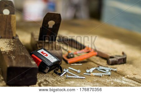 carpenter tools in pine wood table Hammer, pliers and metallic nails. Nail head in focus. Carpentry works.