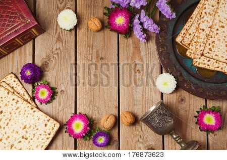 Jewish holiday Passover concept with matza and seder plate over wooden background. View from above