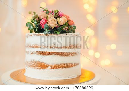 Decorated by flowers white naked cake, rustic style for weddings, birthdays or events.