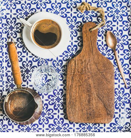 Black Turkish or Eastern style coffee in cup and cezve and wooden board with copy space, oriental Moroccan patterned background, top view