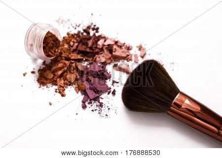 Makeup brush with blush of everyday palette tones sprinkled on white. Make up and female cosmetics background