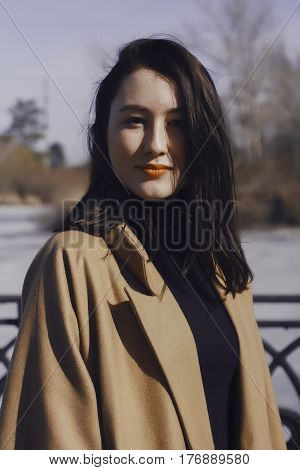 stylish young woman out for a walk. she dressed and looks very fashionable. coat of beige (camel) color and black turtleneck. beautiful woman. the portrait she smiles