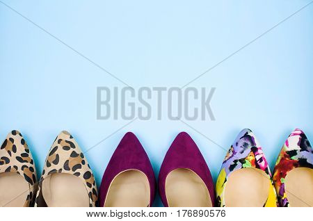 Three pairs of multicoloured stiletto shoes in different patterns on light blue background.