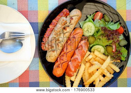 Sausage fried and french fries with vegetables on chintz.
