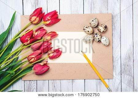 Easter eggsbeautiful red tulips blank note on the wooden background.