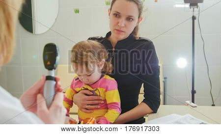Ophthalmology - doctor gives consultations to the mother of the girl about eyesight of little girl - child's healthcare, telephoto