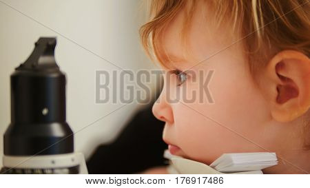 Child's healthcare - little girl in ophthalmological clinic checks eyesight, telephoto