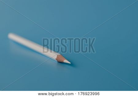 white pancil isolated on a blue background