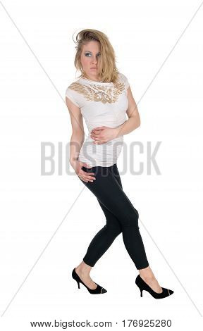 A blond slim young woman standing in black tights and a white blouse and heels isolated for white background.