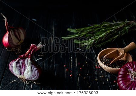 Red onions, rosemary, and spices on a dark table. close up