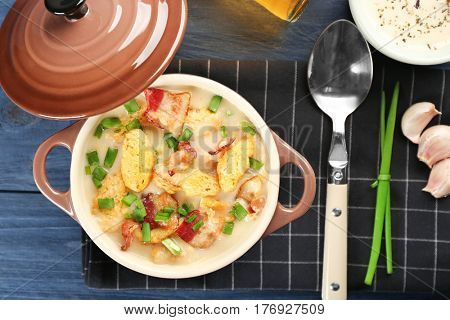 Delicious beer cheese soup with croutons and fried bacon on table