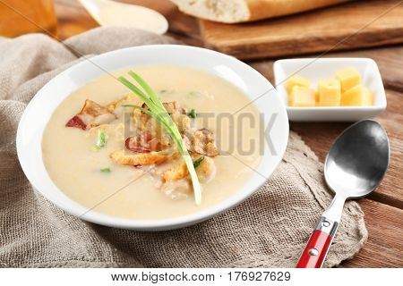 Delicious beer cheese soup with onion and fried bacon on table