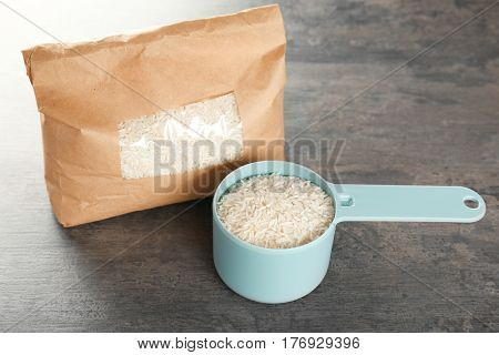 Pack of rice and full measuring scoop on table