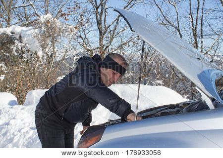 Man checking car engine in the snowy weather