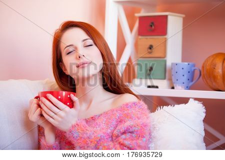 photo of beautiful young woman with cup of coffee relaxing on the sofa