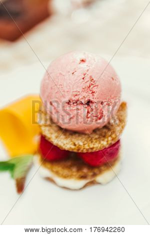 Strawberry ice cream dish with fresh strawberry, fresh cookie and green petal serve on decorated with checkered cloth table
