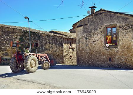SANT-ESTEVE-DE-GUIALBES/ SPAIN - MARCH 28, 2015. A man driving a tractor in old village Sant-Esteve-de-Guialbes. Spain