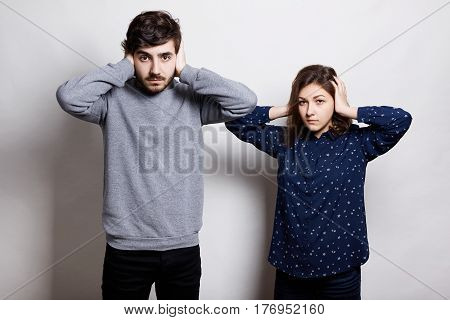 A couple standing over white background being tired of quarreling not wanting to hear each other holding their hands on ears. Bad relationship concept. People and emotions.