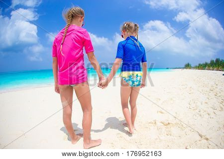 Adorable little girls have fun on white beach during vacation