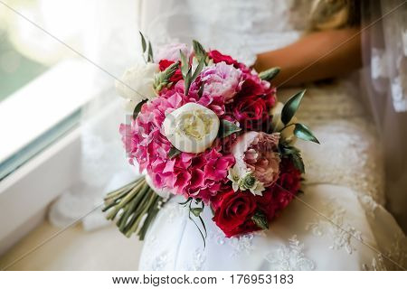Bride holding delicate and tender marriage bouquet in white and pink colours with green petals