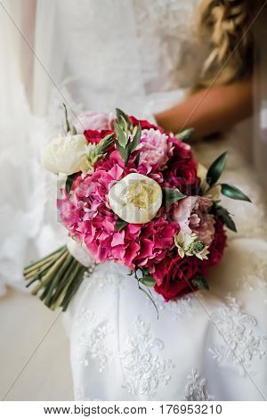 Bride holding delicate and tender marriage bouquet in white and pink colours with green petals