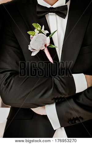 Pink peon boutonniere pinned to a grooms blue jacket