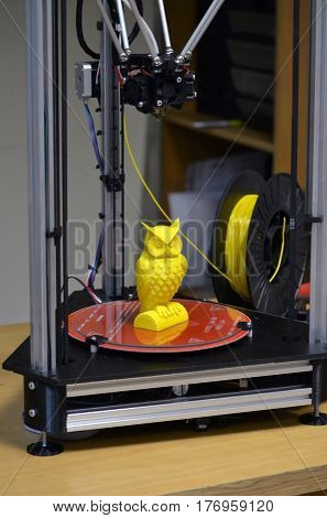 Modern 3D printer printing figure close-up. Automatic three dimensional 3d printer performs plastic yellow colors modeling in laboratory. Progressive modern additive technology