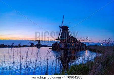 Evening River Zaan with Dutch windmills in Zaandam, Netherlands. Sunset landscape with windmills and field wild herbs and flowers. Sunset landscape with windmills and field wild herbs and flowers.