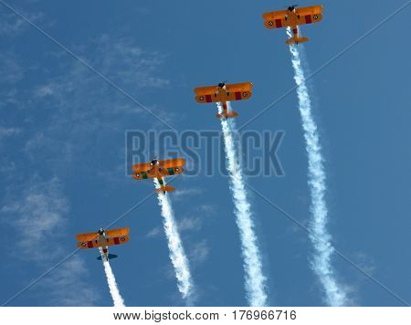 Four Biplanes Climbing in Unison with Smoke Trails