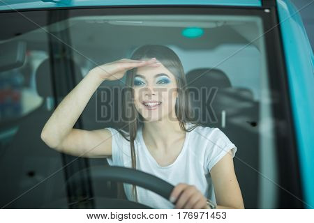 Smiling woman driving car looking streight front