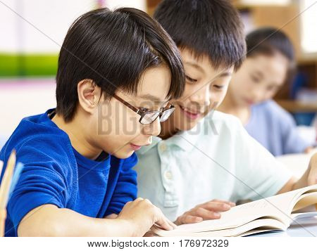 close-up of two asian elementary school pupil studying together in classroom.