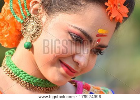 KOLKATA INDIA - MARCH 12 2017: Beautiful young girl with spring festive make up with flowers joyful expression at Holi/Spring festivalknown as Dol (in Bengali) or Holi (in Hindi) celebrating arrival of Spring.