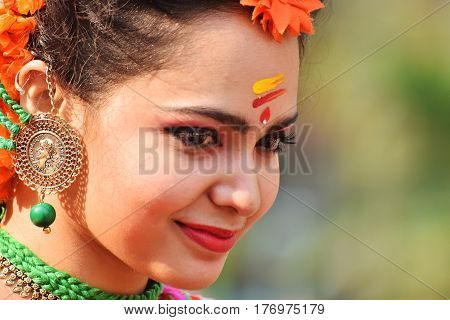 KOLKATA INDIA - MARCH 12 2017: Beautiful young girl with spring festive make up with flowers joyful expression at Holi/Spring festivalknown as Dol (in Bengali) or Holi (in Hindi) celebrating arrival of Spring.